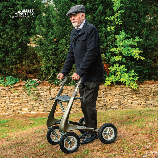 Older man in a flat cap walking up a grassy slope with a byACRE Carbon Overland off-road rollator