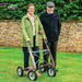 Smiling couple standing arm in arm on a garden lawn, the woman with a Rose Gold byACRE Carbon Overland off-road rollator