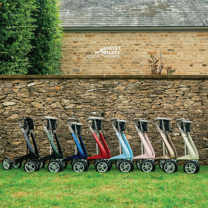 All eight colours of the byACRE Carbon Ultralight rollator lined up beside a Cotswold stone wall and barn