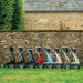 All eight colours of the byACRE Carbon Ultralight rollator lined up beside a Cotswold stone wall and barn