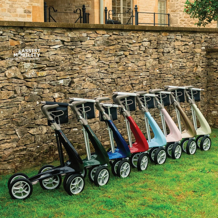 Angled side view of eight byACRE Carbon Ultralight rollators in every colour, from  Carbon Black to Oyster White, on a lawn by a stone wall