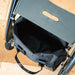 The byACRE Daypack bag unzipped to show its roomy interior, fitted under the seat of a byACRE rollator