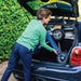 Woman lifting the folded Baltic Blue byACRE Nordic Pioneer rollator into the boot of a Mini Cooper, showing how light and easy it is to load