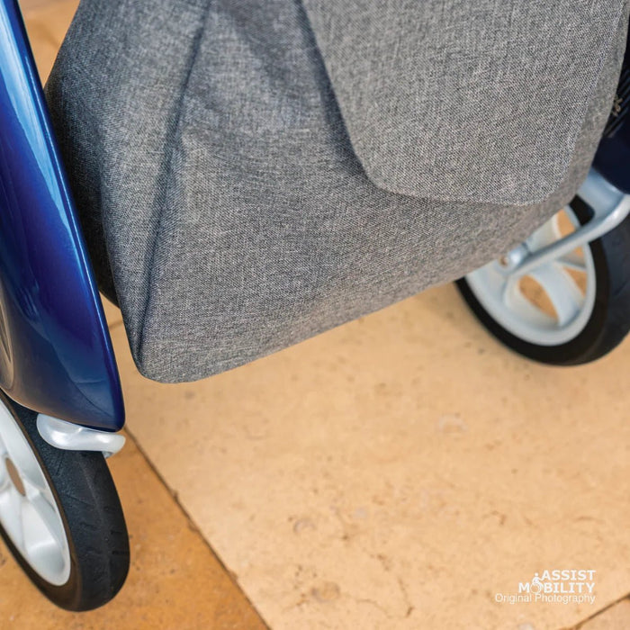 Close-up of the base and grey textured fabric of the byACRE Weekend Bag, hanging between the wheels of a blue byACRE rollator