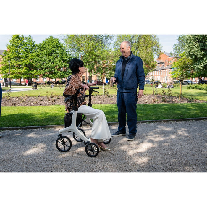 Lady sat on Drive AeroWalk rollator in a park speaking to a gentleman