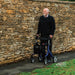 Older man out walking with the Electric Blue Rehasense Space LX rollator in front of a dry stone wall