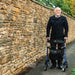 Face-on view of an older man with the Electric Blue Rehasense Space LX rollator, showing its padded seat and storage bag