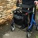 Close-up of the Electric Blue Rehasense Space LX rollator being pushed, showing the padded backrest, seat and Rehasense storage bag