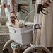 Close-up of a woman placing her handbag in the mesh shopping bag of a Saljol Carbon Superlight rollator