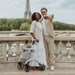 Smiling couple taking a selfie on a Paris bridge with the Eiffel Tower behind, a Saljol Carbon Superlight rollator beside them