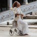 Woman resting on the seat of a Saljol Carbon Superlight rollator beside an ornate Paris bridge on a sunny day