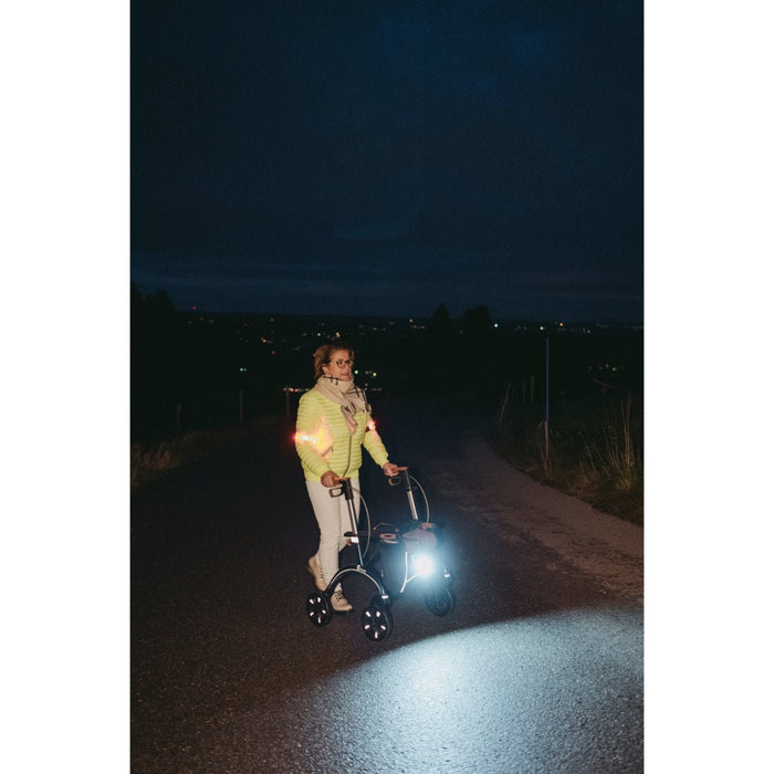 Person using a walker at night time with their LED light on at Assist Mobility