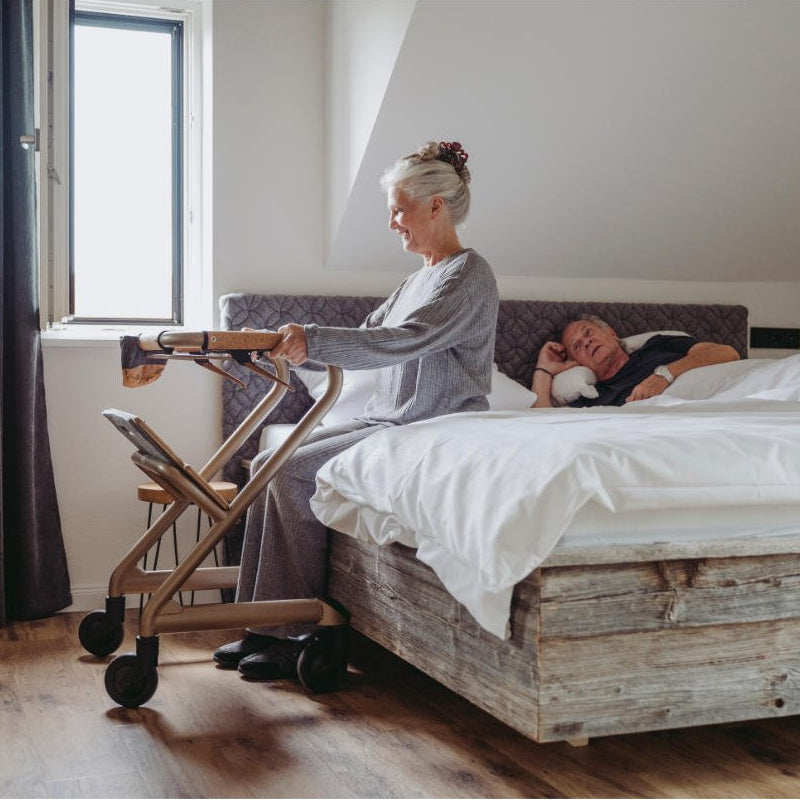 Lady using rollator to help her get into bed - Assist Mobility