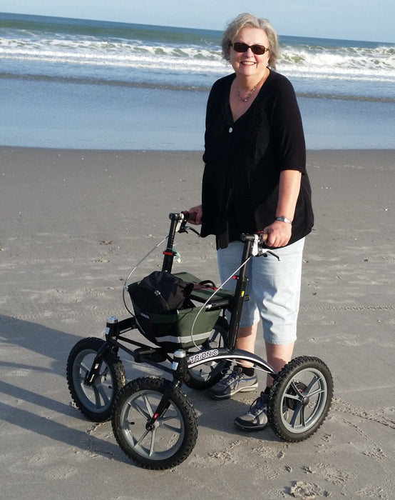 Trionic Rollator with black frame and green bag on a beach at Assist Mobility