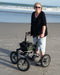 Trionic Rollator with black frame and green bag on a beach at Assist Mobility