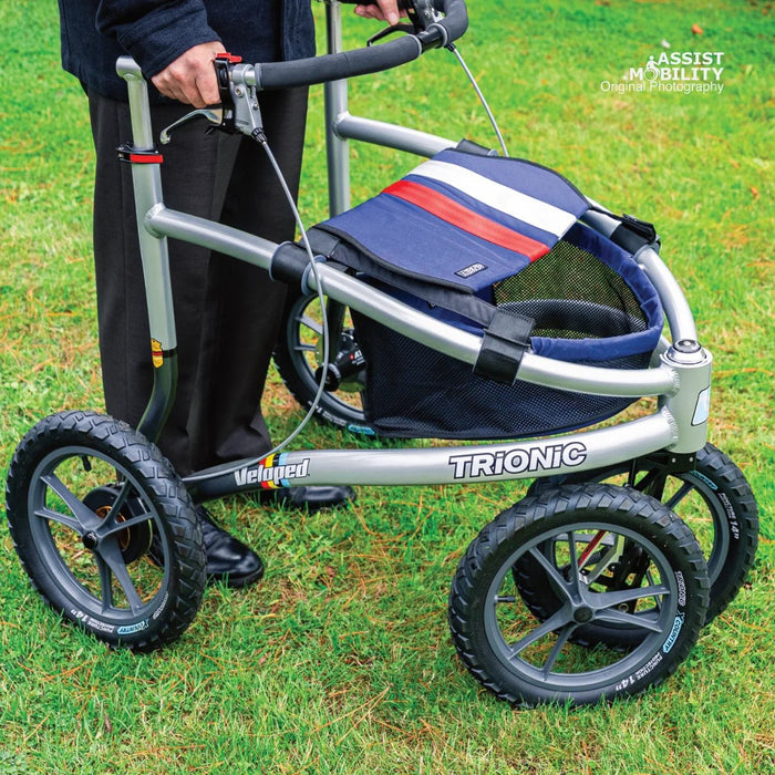Close-up of the Trionic Veloped Sport frame on grass, showing the Trionic logo, chunky off-road tyres and striped storage bag