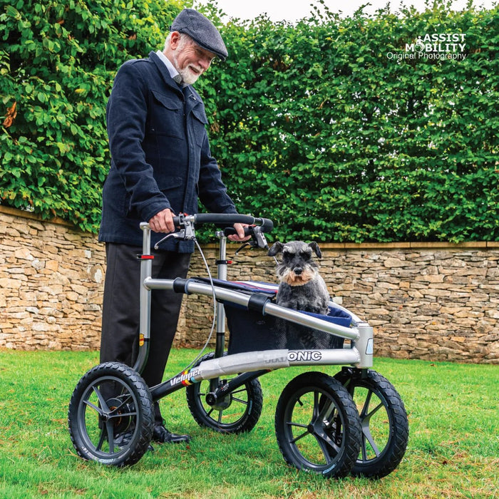 Smiling older man with a Trionic Veloped Sport off-road rollator, his schnauzer dog sitting in the rollator's bag