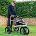 Smiling older man with a Trionic Veloped Sport off-road rollator, his schnauzer dog sitting in the rollator's bag