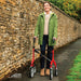 Smiling woman standing tall with the red Trust Care Let's Fly rollator on a path beside a Cotswold stone wall