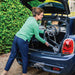 Smiling woman easily loading the folded Trust Care Let's Fly rollator in dark grey into a small car boot