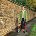 Happy woman walking with the red Trust Care Let's Fly rollator beside a Cotswold stone wall on an autumn day