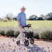 Saljol ALU rollator.  Lightweight and easy to use.  Gentelman walking on gravel with lavender borders to the path.